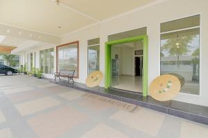 a building with green doors and benches on the sidewalk at Hotel Srikandi Syariah Mitra RedDoorz in Tasikmalaya