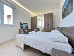 a white bedroom with a large white bed and a window at Moderno appartamento dí Beniamino Murgioni a Villasimius in Villasimius