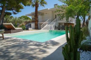 a swimming pool in front of a house with palm trees at Villa Helio Kineta in Kineta