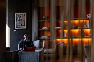 a man sitting in a chair talking on a cell phone at ANA InterContinental Tokyo by IHG in Tokyo