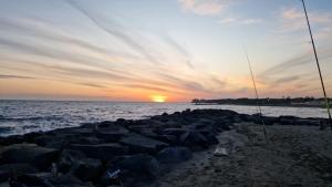 a sunset over the ocean with rocks on the beach at Marilyn House in Ladispoli
