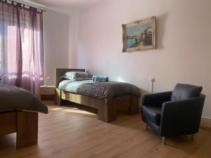 ein Schlafzimmer mit einem Bett und einem Stuhl in der Unterkunft Les 2 suites de Belfort 184m2 Centre Parkings in Belfort