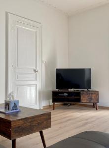 ein Wohnzimmer mit einem Flachbild-TV und einem Couchtisch in der Unterkunft Les 2 suites de Belfort 184m2 Centre Parkings in Belfort