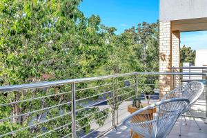 a balcony with two chairs and trees at Urban Junction - Walk to Mawson Lakes Dining & Shops in Mawson Lakes