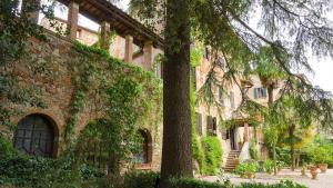 un gran edificio de ladrillo con un árbol delante de él en Residenza d'Epoca Il Cassero, en Lucignano