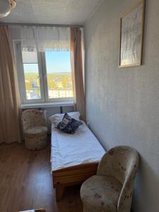 シフィノウイシチェにあるSurfers Apartmentのベッド1台、椅子2脚、窓が備わる客室です。