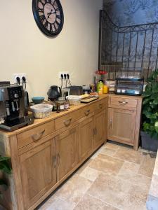 a kitchen with wooden cabinets and a clock on the wall at Domaine de Lithos in Fossemagne