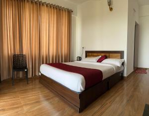 a bedroom with a large bed and a chair at Olivet Homestay in Vagamon