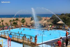 a large swimming pool with people in it next to a beach at Mobile home in Sérignan
