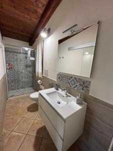 ein Badezimmer mit Waschbecken, Toilette und Spiegel in der Unterkunft La Botte e il Vino Rooms in Capoterra