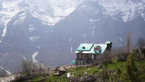 a house on a hill with mountains in the background at Shrenbute Cottage in Tāndi