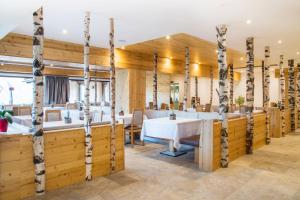 a dining room with wooden walls and tables and trees at Sporthotel Kalcherhof in Racines