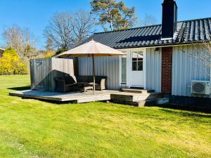 a patio with an umbrella and a chair on a deck at Close to the Beach, Large Garden with 2 Patios & BBQ in Falkenberg