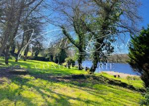 un parco con panchina, alberi e lago di "Les Bonnes Ondes" aux gîtes de l'Etang Neuf by Kastell Breizh a Saint-Connan
