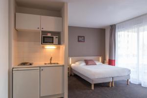 1 dormitorio pequeño con 1 cama y cocina en Appart'City Classic La Rochelle Centre en La Rochelle