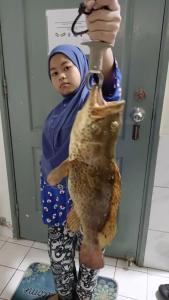 a young girl holding a fish on a hook at Ground floor apartment Seaview beach in Port Dickson