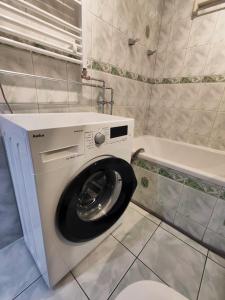 a white washing machine in a bathroom with a tub at Apartament w centrum Helu in Hel