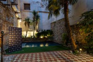 a swimming pool in a courtyard with a palm tree at 5 Sentidos - Suites de Lujo in Tudela