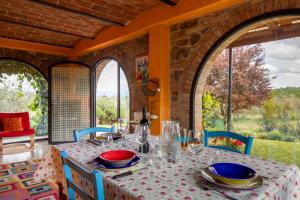a dining room with a table and chairs and windows at Il Poggio Dell'Eremita in Rigomagno