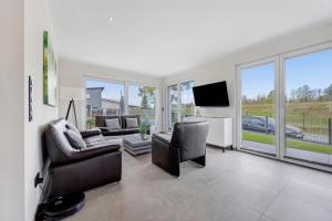 a living room with couches and a tv and windows at Ferienwohnung Bresser Bernsteinsee in Sassenburg