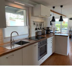 a kitchen with white cabinets and a sink and a window at Ferienhaus Solken mit großer Terrasse und Kaminofen in Plau am See