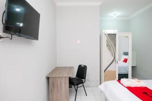 a bedroom with a bed and a desk and a tv at RedDoorz Syariah at Joa Homestay Goodean Sleman Yogyakarta in Godean