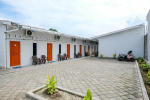 a white building with orange doors and a patio at RedDoorz Syariah at Joa Homestay Goodean Sleman Yogyakarta in Godean +27 photos