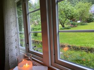 a candle sitting on a table in front of a window at Lite hus i hagen in Malvik +3 photos