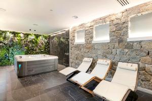 a bathroom with a stone wall and a tub and chairs at Aldiana Club Rocca Nettuno Calabria in Tropea