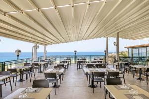 a restaurant with tables and chairs and the ocean at Aldiana Club Rocca Nettuno Calabria in Tropea