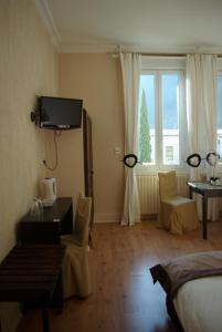 a bedroom with a bed and a desk and a window at Auberge Du Parc in Orgon