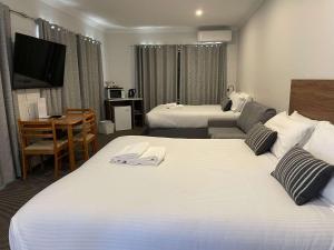 a hotel room with two beds and a television at Mudgee Vineyard Motor Inn in Mudgee