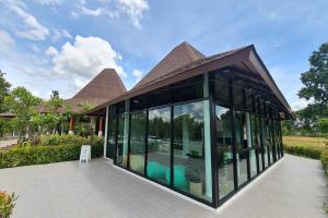 a glass house with a roof at Phorpun Resort Lampang in Ban Mai