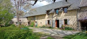 an old stone house with red doors and windows at Chambre d'hôte in Meymac