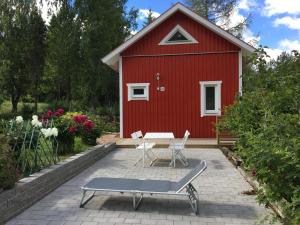 a red shed with a table and chairs in front of it at Sjöstuga, lake view cottage in Spersboda +18 photos