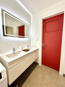 La salle de bains est pourvue d'une porte rouge et d'un lavabo. dans l'établissement La Jonquille, Appartement Centre Ville de Gérardmer, linge et ménage inclus, à Gérardmer 13 autres photos