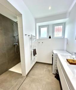 une salle de bain blanche avec une douche et un lavabo dans l'établissement La Jonquille, Appartement Centre Ville de Gérardmer, linge et ménage inclus, à Gérardmer