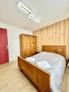 une chambre avec un grand lit et des murs en bois dans l'établissement La Jonquille, Appartement Centre Ville de Gérardmer, linge et ménage inclus, à Gérardmer