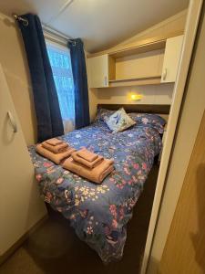 a small bedroom with a bed with towels on it at Lovely Serenity 1 and 2 caravans are situated on the Norfolk Broads in Lowestoft