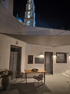 a table and chairs with a clock tower in the background at Imarkellis Santorini Cave House with yard in Pyrgos