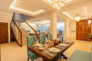 una sala da pranzo con tavolo in legno e sedie verdi di ELIVAAS privé Royce Cottage Hilltop 4 BHK Retreat With Indoor Bar, Terrace & Scenic Views a Kasauli