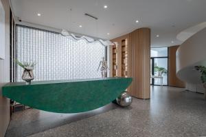 een groen bad in een kamer met een muur bij Xinchi Sakura Valley Resort in Shaoxing