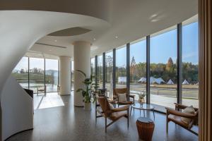 een lobby met stoelen, een tafel en glazen ramen bij Xinchi Sakura Valley Resort in Shaoxing