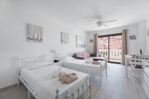 a white bedroom with two beds and a living room at Estupendo Estudio En Castle Harbour in Los Cristianos +19 photos