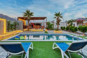 a swimming pool with two chairs and a house at 800 Mountain Resort Vacation House in Fujairah