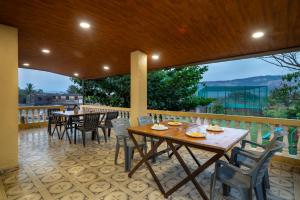 a patio with tables and chairs on a balcony at Newly Renovated-Farm Villa -6BHK with Pool & Turf in Lonavala
