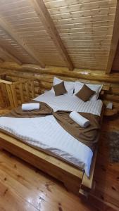 a bed in a log cabin with white sheets and pillows at Intim Chalet in Avrig