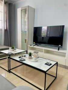 a living room with two tables and a flat screen tv at Ilios & Thalassa Luxury Retreat , Ofrinio in Ofrínion