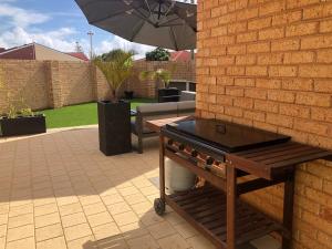 a barbecue grill on a patio with an umbrella at BackersBeach Villa in Geraldton