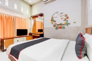 a bedroom with a white bed and a television at Hotel O Yogyakarta near Jogja City Mall formerly Bama Guesthouse in Yogyakarta